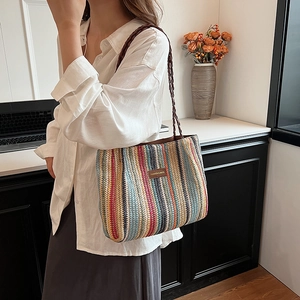 Détail d'un sac cabas tissé à rayures multicolores avec logo en cuir et bandoulière