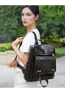 Detail of a black synthetic leather backpack with stitched texture and metal buckle on straps
