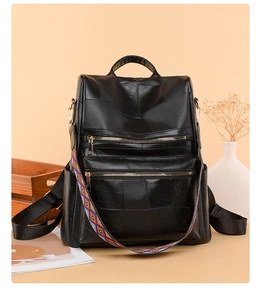 Detail of black soft leather backpack with parallel zippers and colorful patterned strap