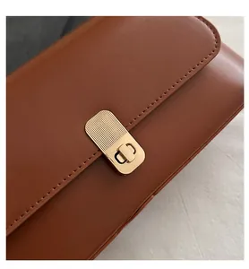 Close-up of a vintage brown leather bag featuring a textured gold rectangular clasp