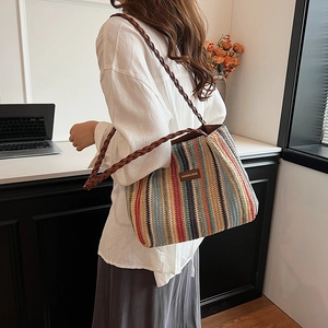Détail du sac cabas en paille à rayures multicolores avec étiquette en cuir et bandoulière