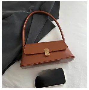 Detailed top view of a brown vintage baguette bag with gold buckle next to a phone for scale