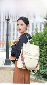 Close-up of beige soft leather backpack featuring textured finish and colorful woven strap