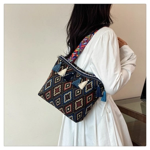 Close-up of bohemian shoulder bag with colorful geometric patterns and blue tassels