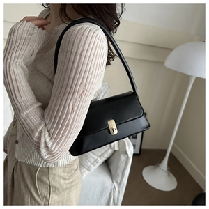 Detailed close-up of a black rectangular underarm bag featuring a gold metal buckle