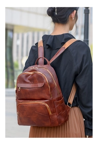 Detail of dark brown leather backpack with geometric stitching and multiple zippers