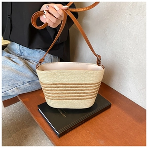 Detail of woven straw bag with beige and brown stripes placed on vintage books