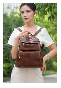 Detail of a dark brown leather backpack featuring geometric patchwork and gold zippers