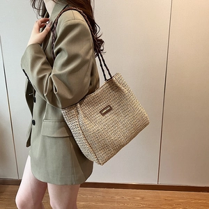 Gros plan d'un sac cabas en paille tissée avec anses tressées et logo en cuir élégant