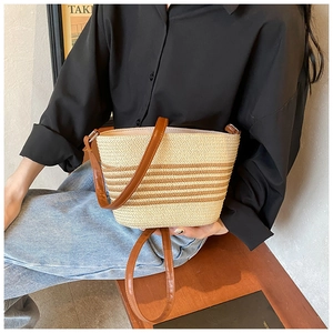 Detail of woven straw bucket bag with brown leather strap and striped texture