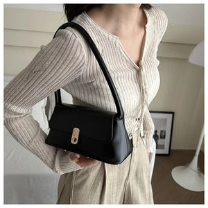 Detail of a vintage black baguette bag with elegant golden turn-lock on the front flap