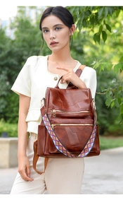 Detail of vintage brown leather backpack featuring a bohemian geometric woven strap