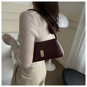 Fashionable dark burgundy baguette bag with gold metal buckle shown on female shoulder