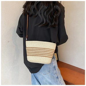 Detail view of woven straw crossbody bag with striped pattern on a female model