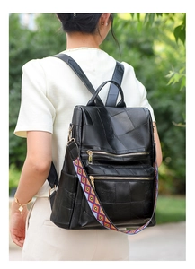 Detail of black leather backpack with geometric patterns and colorful woven strap