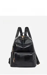 Front detail of black oxford fabric backpack featuring gold metal zippers and multi-pocket design