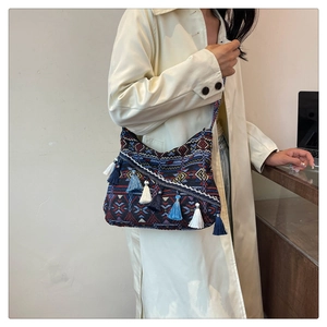 Close-up of ethnic style shoulder bag with bohemian tassels and colorful geometric patterns