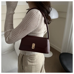 Deep burgundy leather baguette bag with gold twist lock shown on model's shoulder