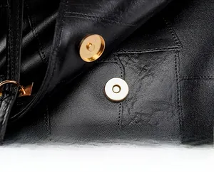Close-up of golden magnetic snap closure on black lychee texture leather backpack