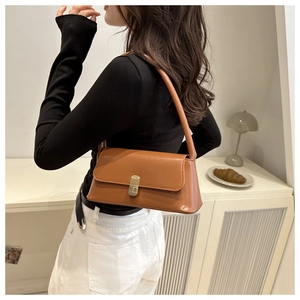 Detail of vintage brown baguette bag with gold logo buckle worn by model on shoulder