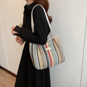 Colorful striped woven tote bag with rope handles shown on a model's shoulder