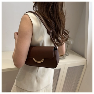 Detail of dark brown matte leather shoulder bag with a gold crescent buckle and knot strap