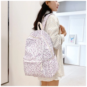 Detail view of a floral canvas backpack showing the side pocket and front zipper pouch