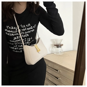 Détail du sac croissant en cuir blanc avec fermoir doré pour un look élégant