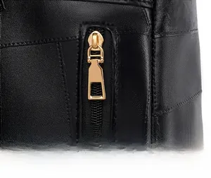 Close-up of smooth gold metal zipper and stitching on a black textured leather backpack