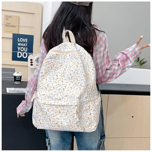 Floral canvas backpack detail showing yellow and purple patterns on beige fabric