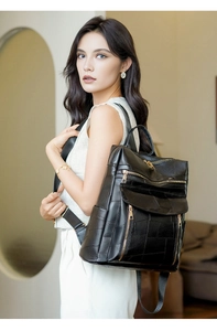 Détail d'un sac à dos en cuir noir avec motif patchwork et fermetures éclair dorées