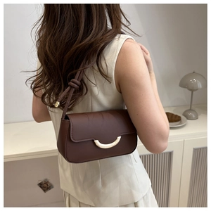 Detail of dark coffee leather shoulder bag with gold crescent buckle and knot strap detail