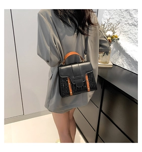 Detail of urban minimalist crossbody bag with woven texture and brown handle in model shot