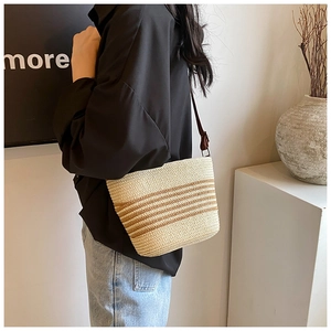 Detail of handwoven straw shoulder bag with beige and brown stripes and leather strap