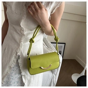Detail of lime green underarm bag with gold metal buckle on floral dress background