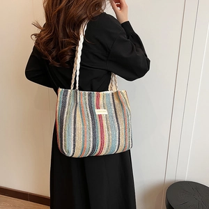Détail d'un grand sac cabas tissé à rayures colorées avec des bandoulières tressées blanches