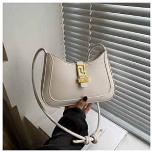 Detail van beige leren halve maan tas met gouden geometrische sluiting en geknoopte riem