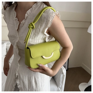 Detail of lime green underarm bag featuring knotted strap and golden semi-circle buckle
