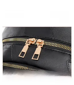 Close-up of black leather backpack with dual gold metal zippers and smooth texture