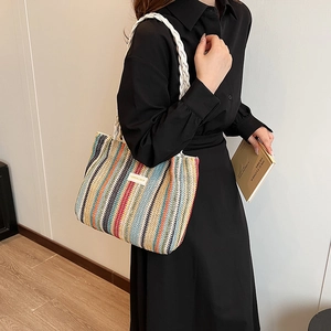 Gros plan d'un sac cabas en paille tissé avec rayures colorées et anse blanche