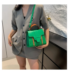 Detail of green crocodile-embossed leather handbag with brown handle and gold hardware