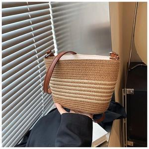 Detail of woven straw bucket bag with dark brown leather strap for summer beach vacation