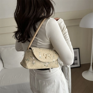 Beige woven baguette shoulder bag with floral embroidery and golden bow buckle