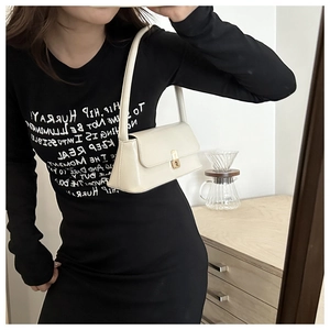 Detail of cream baguette bag with gold twist lock styled with a black cotton T-shirt