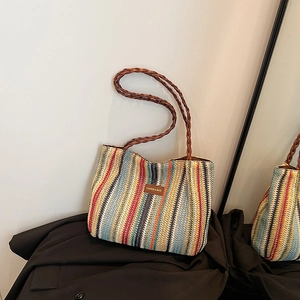Détail d'un sac cabas en paille tissée colorée avec écusson en cuir et anses en corde