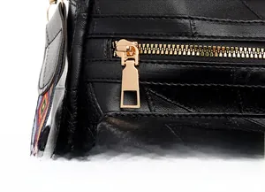 Detailed macro view of black crocodile embossed leather with premium gold metal zipper