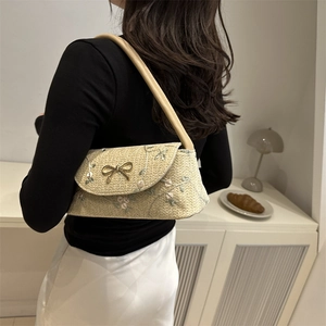 Beige woven baguette shoulder bag with floral embroidery and golden bow metal clasp
