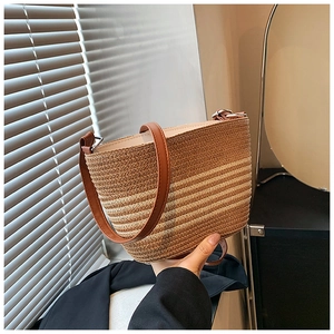 Detail of woven straw bucket bag with brown leather handles and striped texture