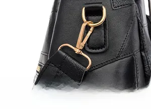 Detail of black leather backpack showing detachable shoulder strap with gold metal buckle