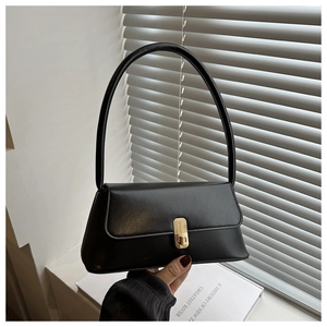 Detail of a vintage black baguette bag featuring a gold buckle and matte leather texture